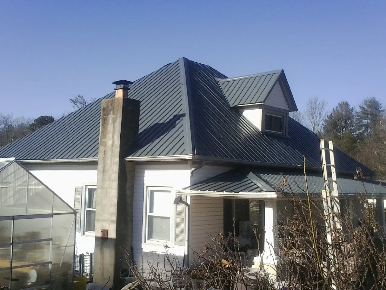 Dark blue standing seam metal roof on a white farmhouse with dormer — Slate & Tile Roof Repair by Roofing Brothers in Ottawa