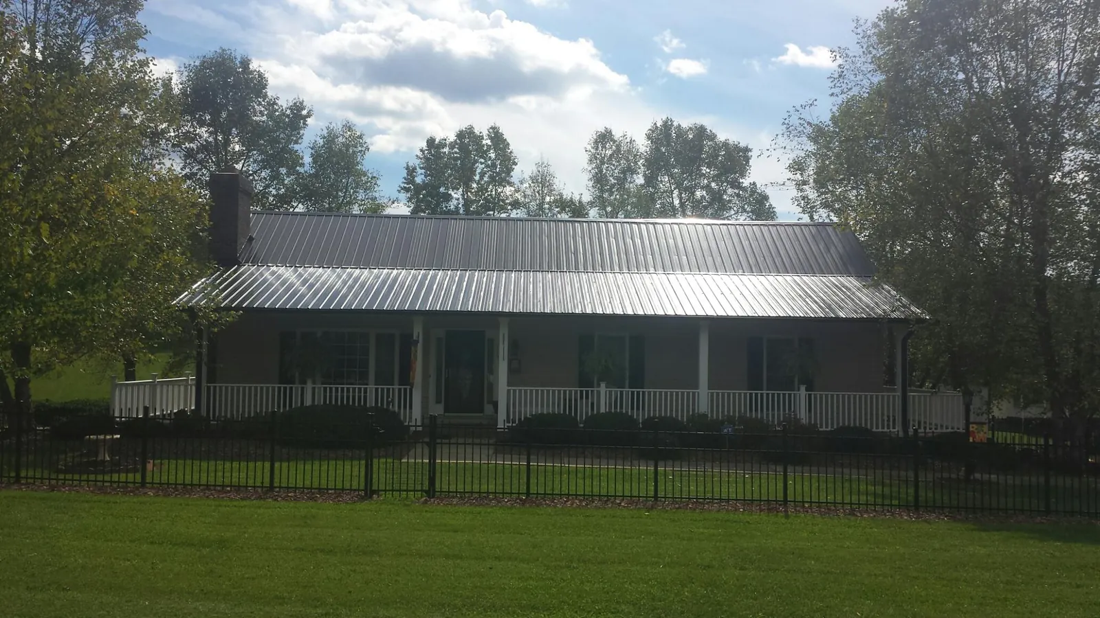 Gray metal roof on a brick ranch with a full width front porch — Gutter Guard Installation work by our crew in Ottawa